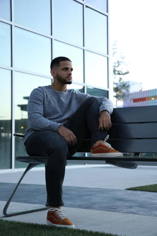 young man in gray sweater sitting on park bench