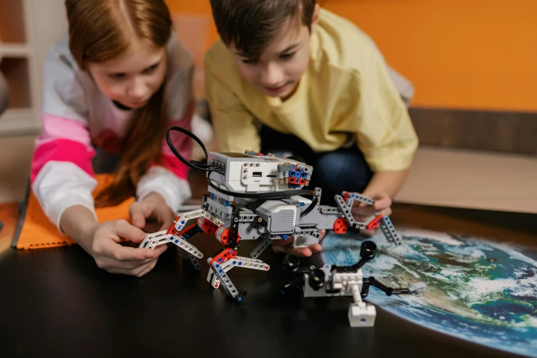 two girls sitting at a table with lego technics