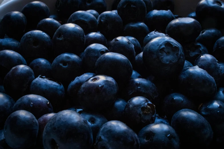 a close up po of blueberries in a white bowl