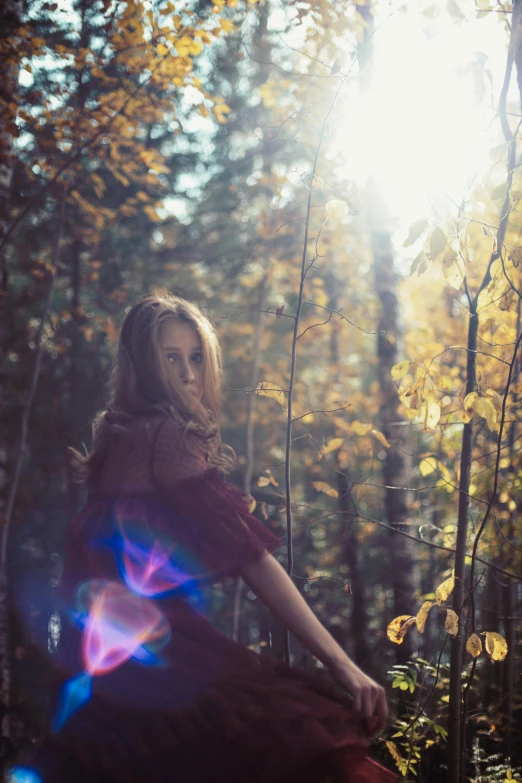 the woman is posing in the woods wearing a long red dress