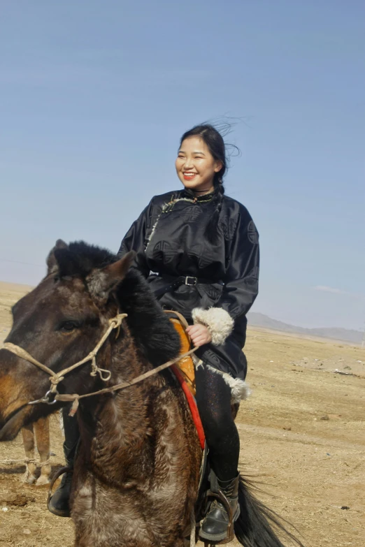 a woman smiles as she rides a brown horse