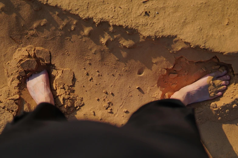 a view of two people with their feet in the sand