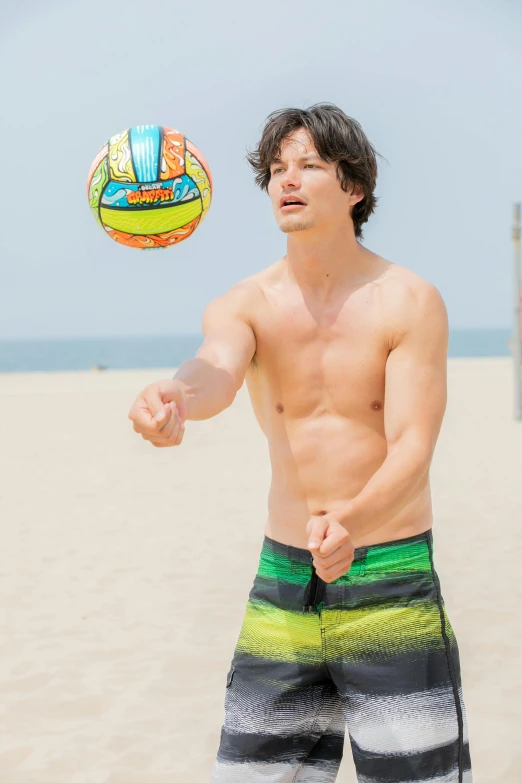 a man standing on the beach with a beach volleyball