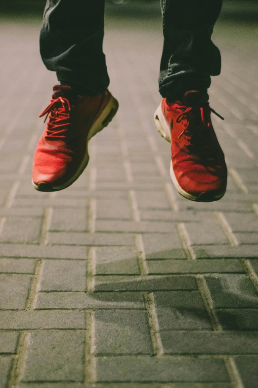 a person's feet in a red tennis shoe