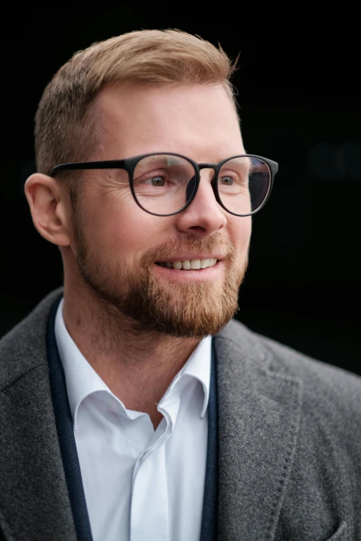 a bearded man wearing glasses and a suit