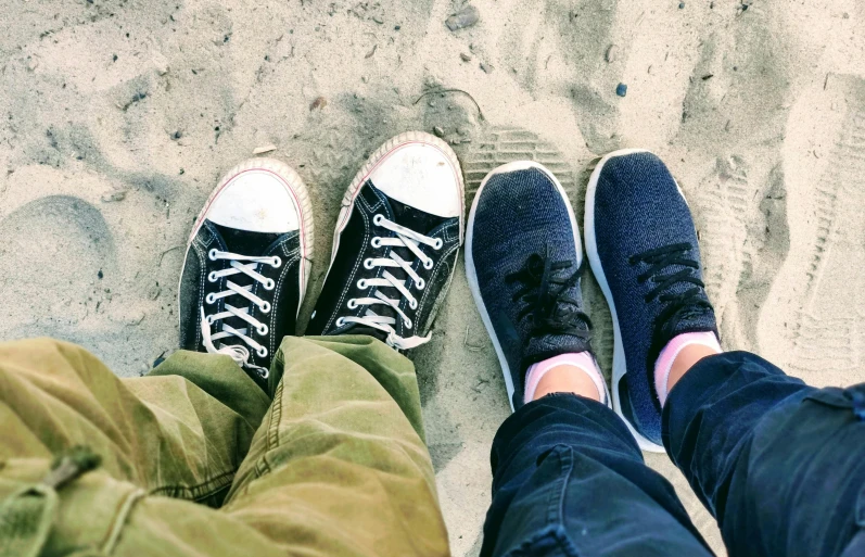 two people are sitting on a beach next to each other