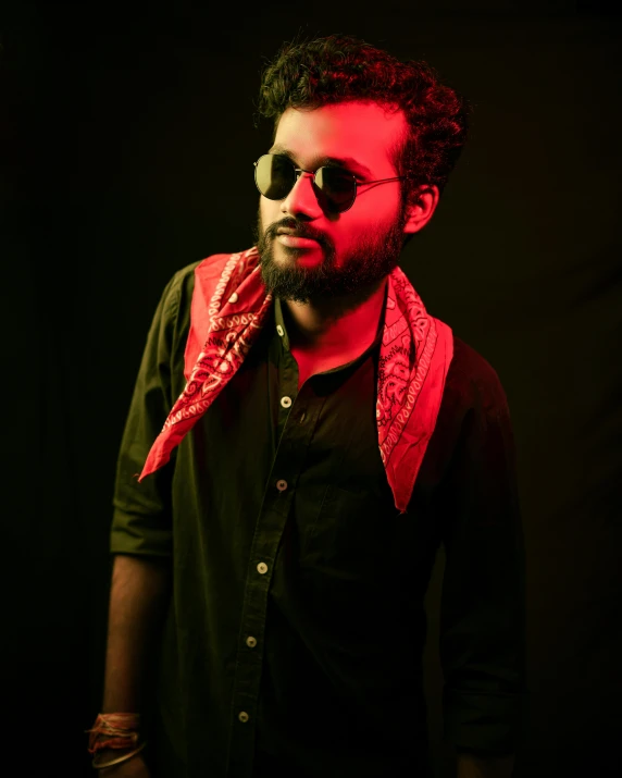 a man with sunglasses holds up a red umbrella