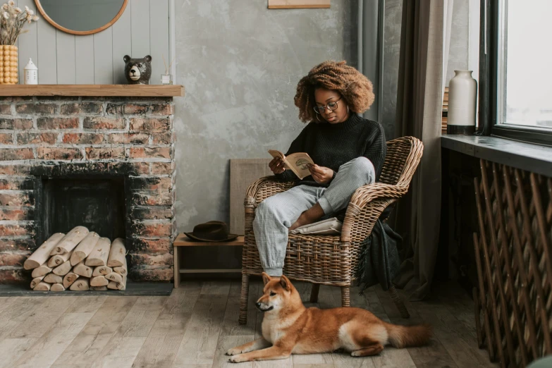 a woman is reading a book while sitting in a wicker chair