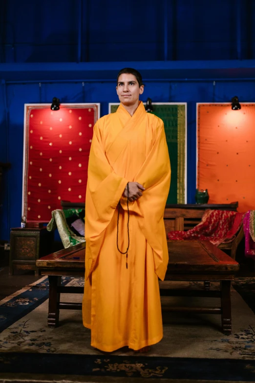 a monk dressed in bright orange poses for a pograph