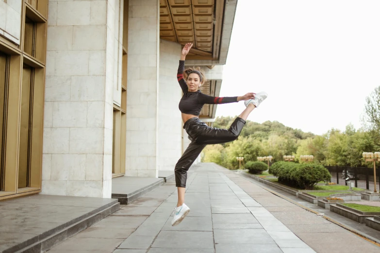 a girl does a dance move outside a building