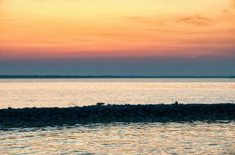 a small boat floating near shore at sunset