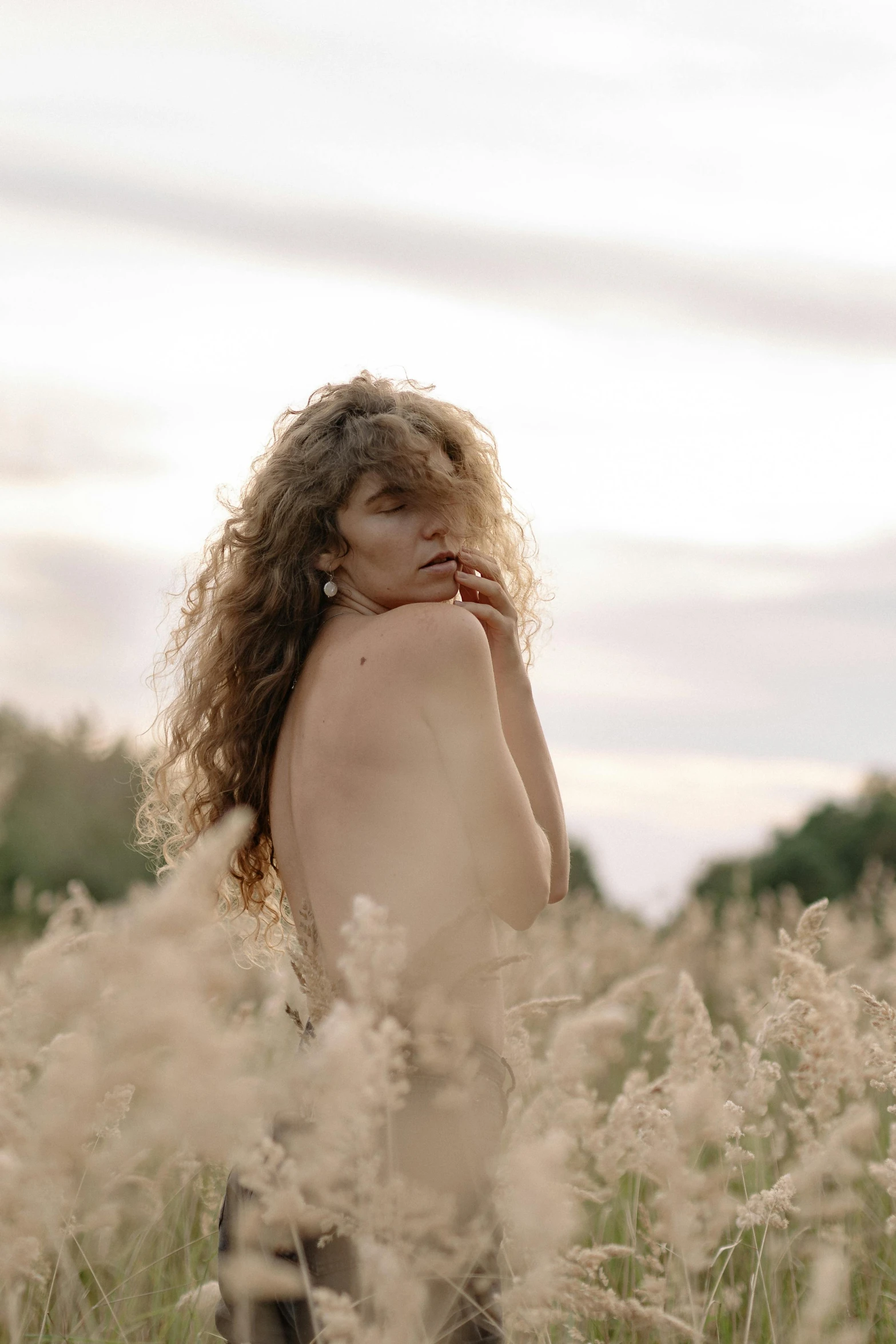  woman in a field standing  holding a cigarette