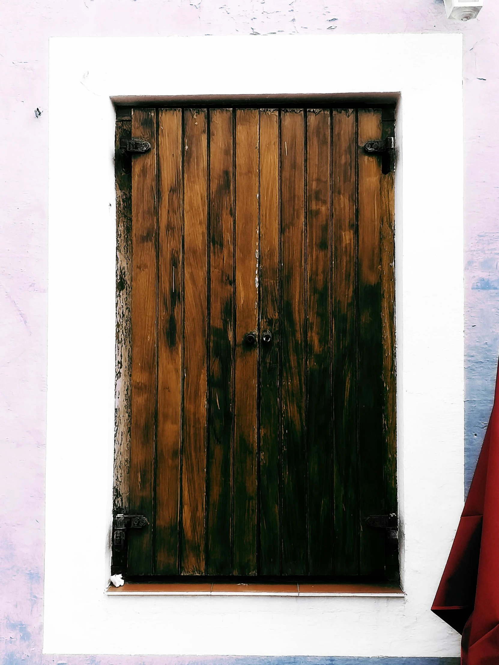 a small red bag sitting next to a white building