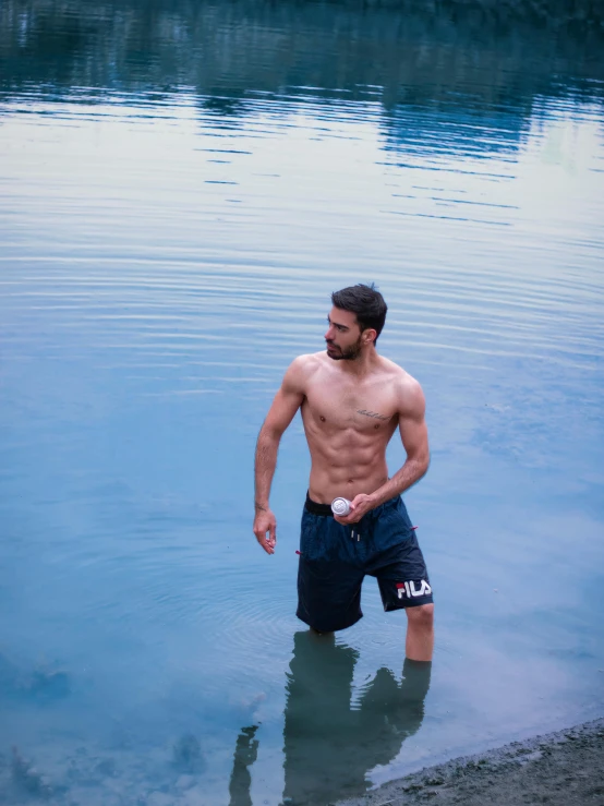 a young man standing in water holding his hand to his waist