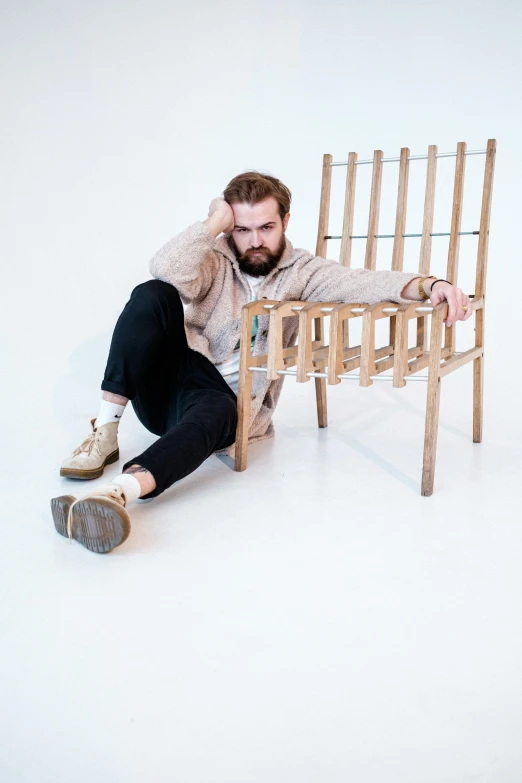 a man is sitting on a wooden chair