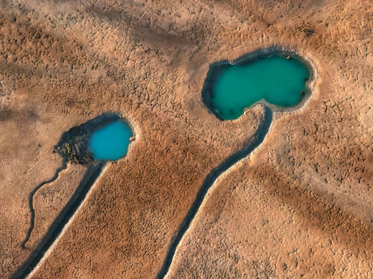 two small lakes in a sandy plain with one blue