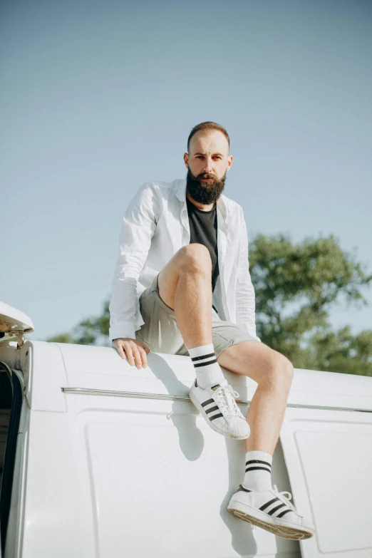 a man sitting on the hood of a van wearing white socks