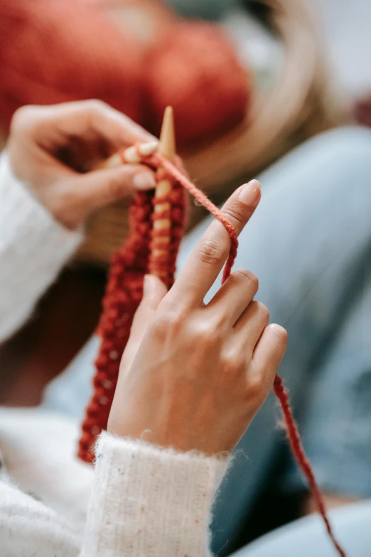 a woman is knitting in a class on her cell phone