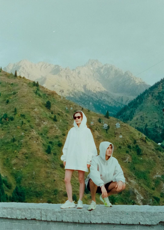 two people in white jackets stand on a cliff side