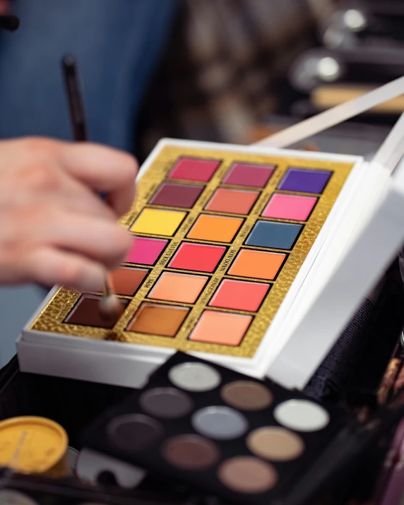 closeup of a person's hand holding a palette and eye shadow swatter