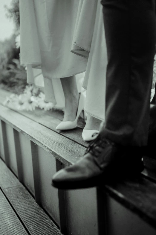 legs in wedding shoes on a wooden bench