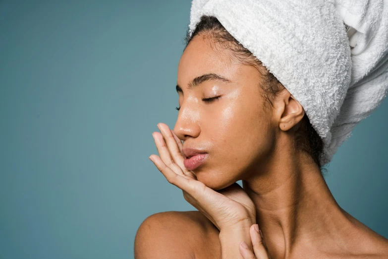 a woman in a towel covering her face with soap