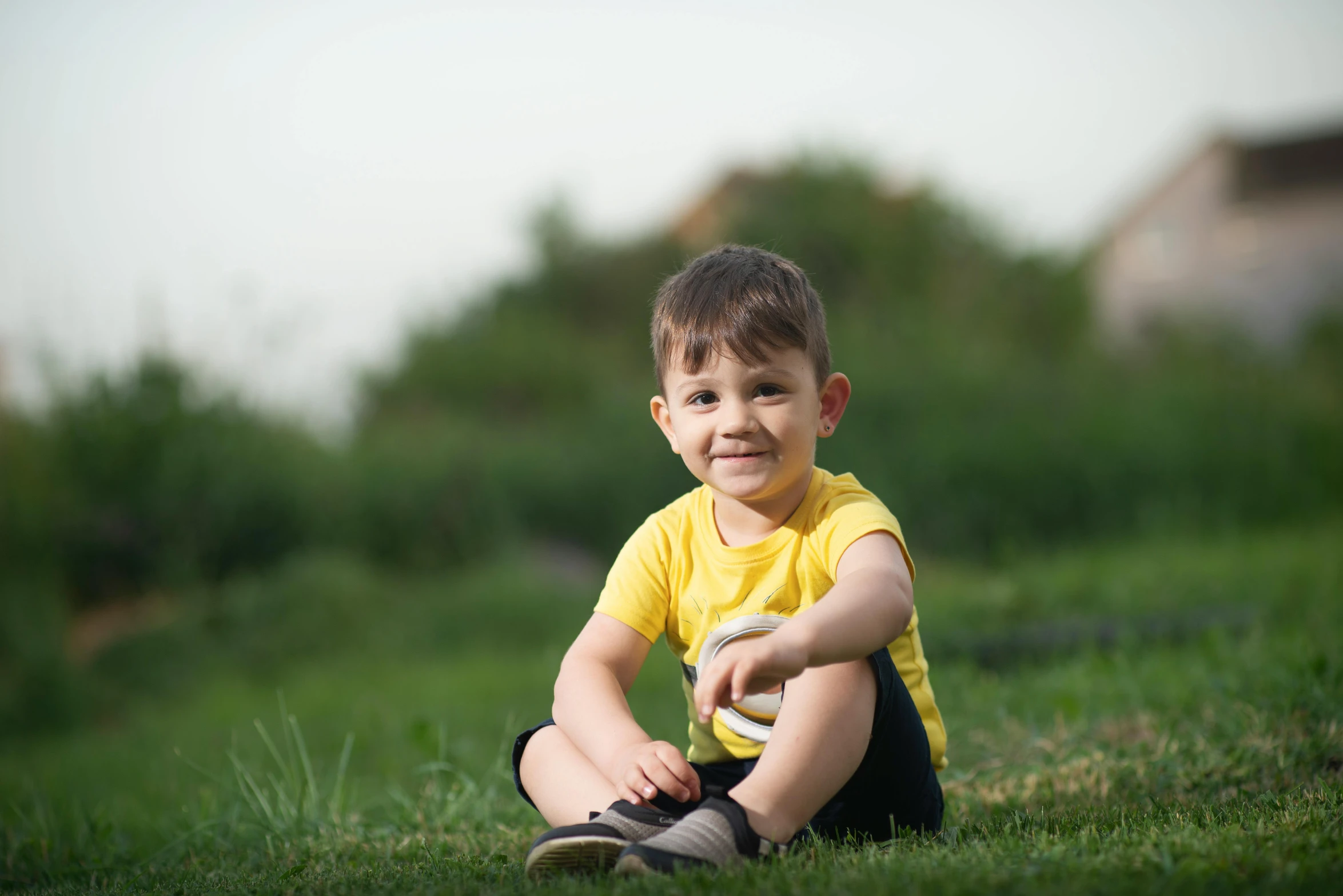 the little boy is smiling while sitting in the grass