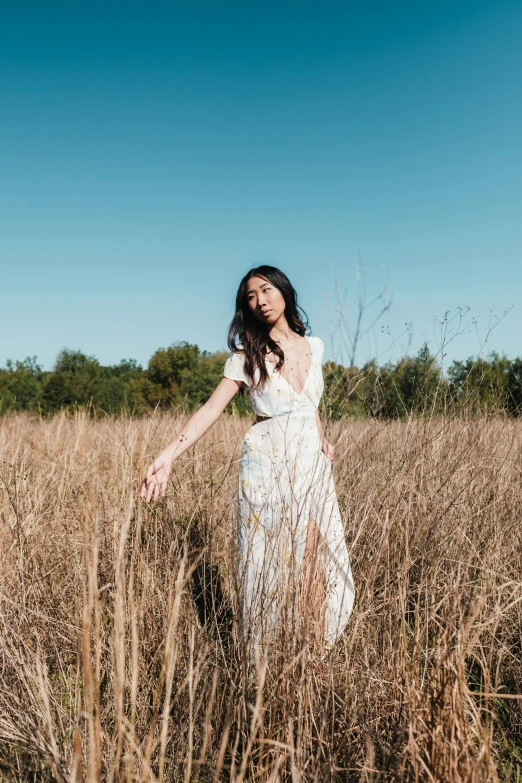 a young woman is standing in the middle of tall grass