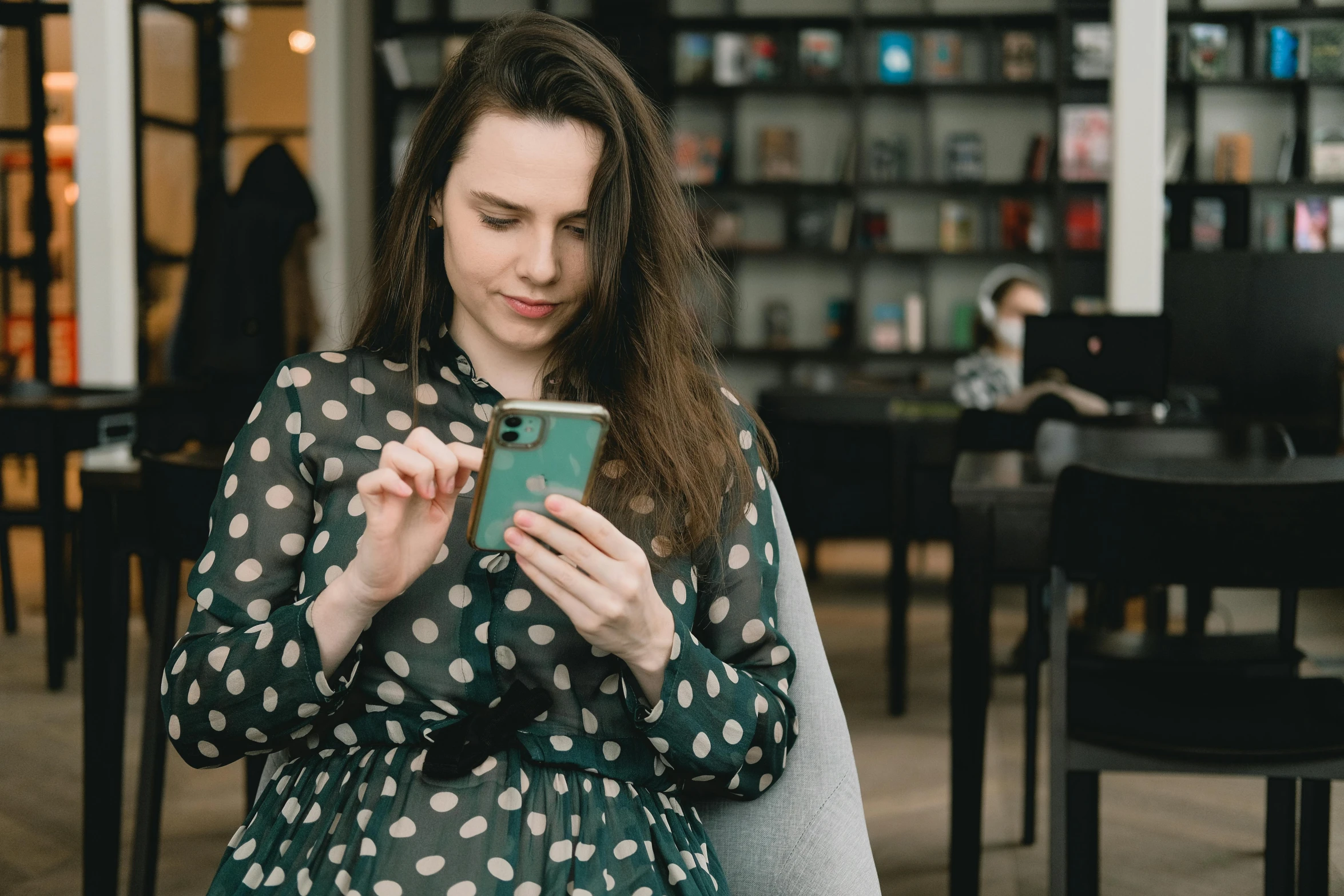 young woman in a polka dot blouse looking at her cellphone