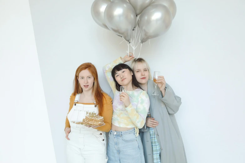 three women posing for a picture with silver balloons