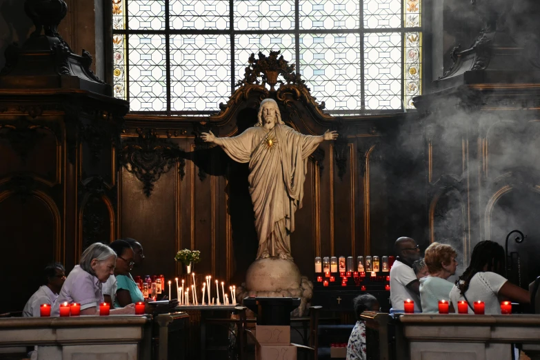 people are in front of the statue with candles on it