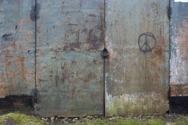 a rusty door with a stencil of an anarchy sign on it