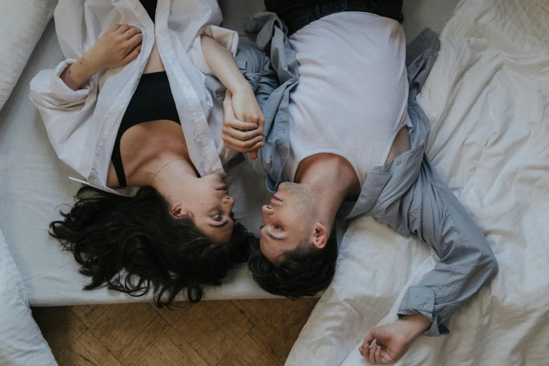 two people are lying in bed and looking at each other