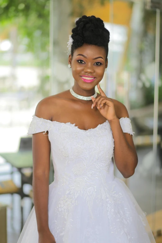 a young african bride wearing a strapless white wedding dress and standing in an office lobby