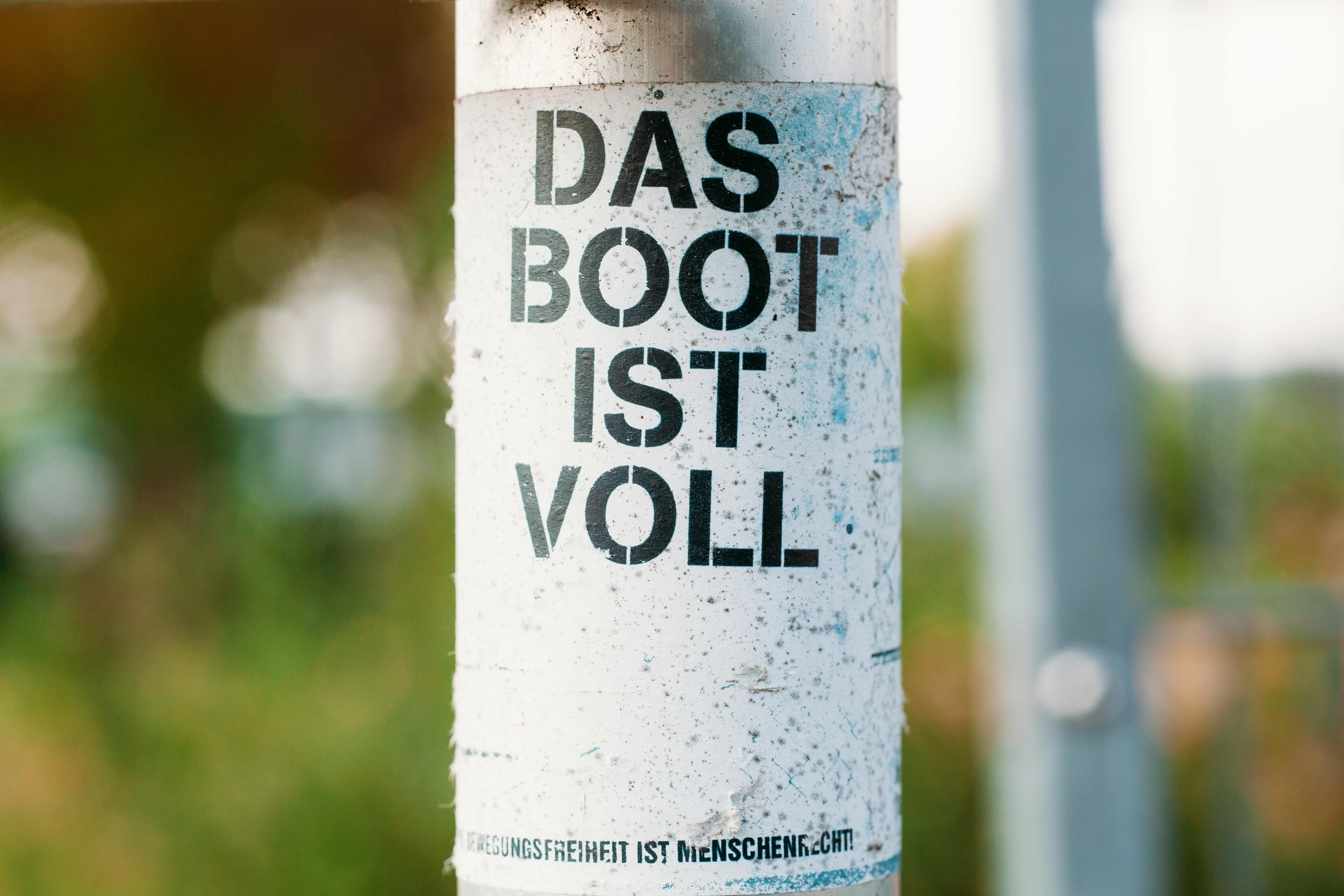 an advertit on a white pole next to grass