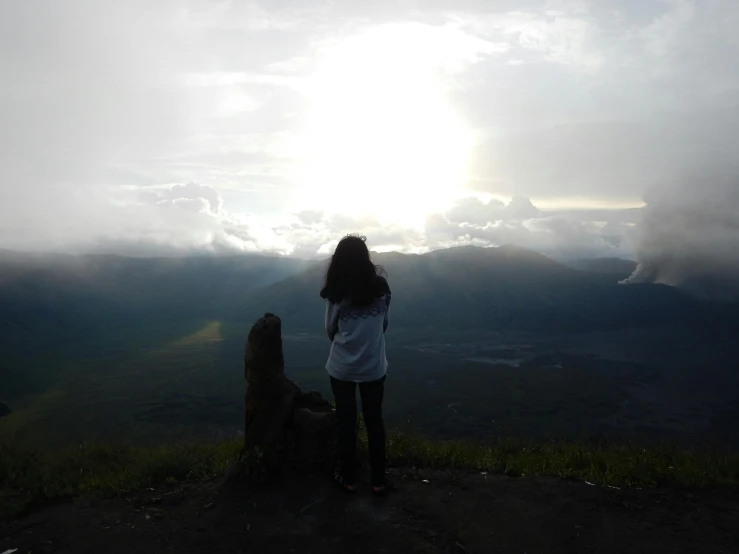 woman standing alone at top of mountain looking over valley