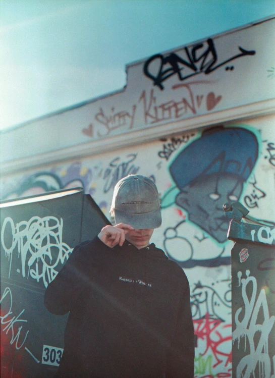a man riding a skateboard next to a wall with graffiti on it