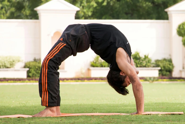 a man doing yoga in a yard with green grass