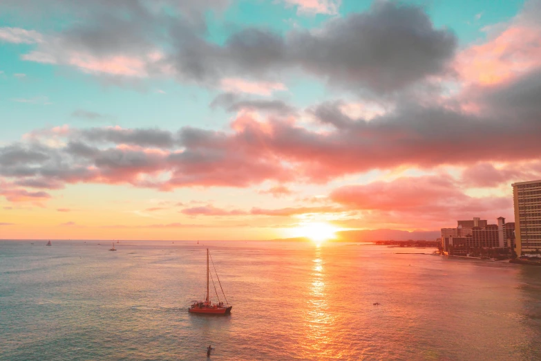 sunset over the ocean with buildings and boats