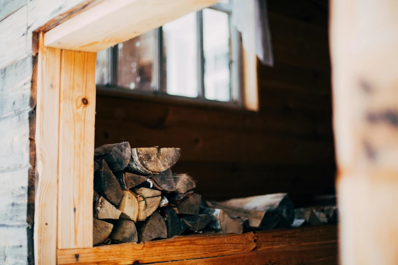 stacked firewood is near the window in a rustic cabin