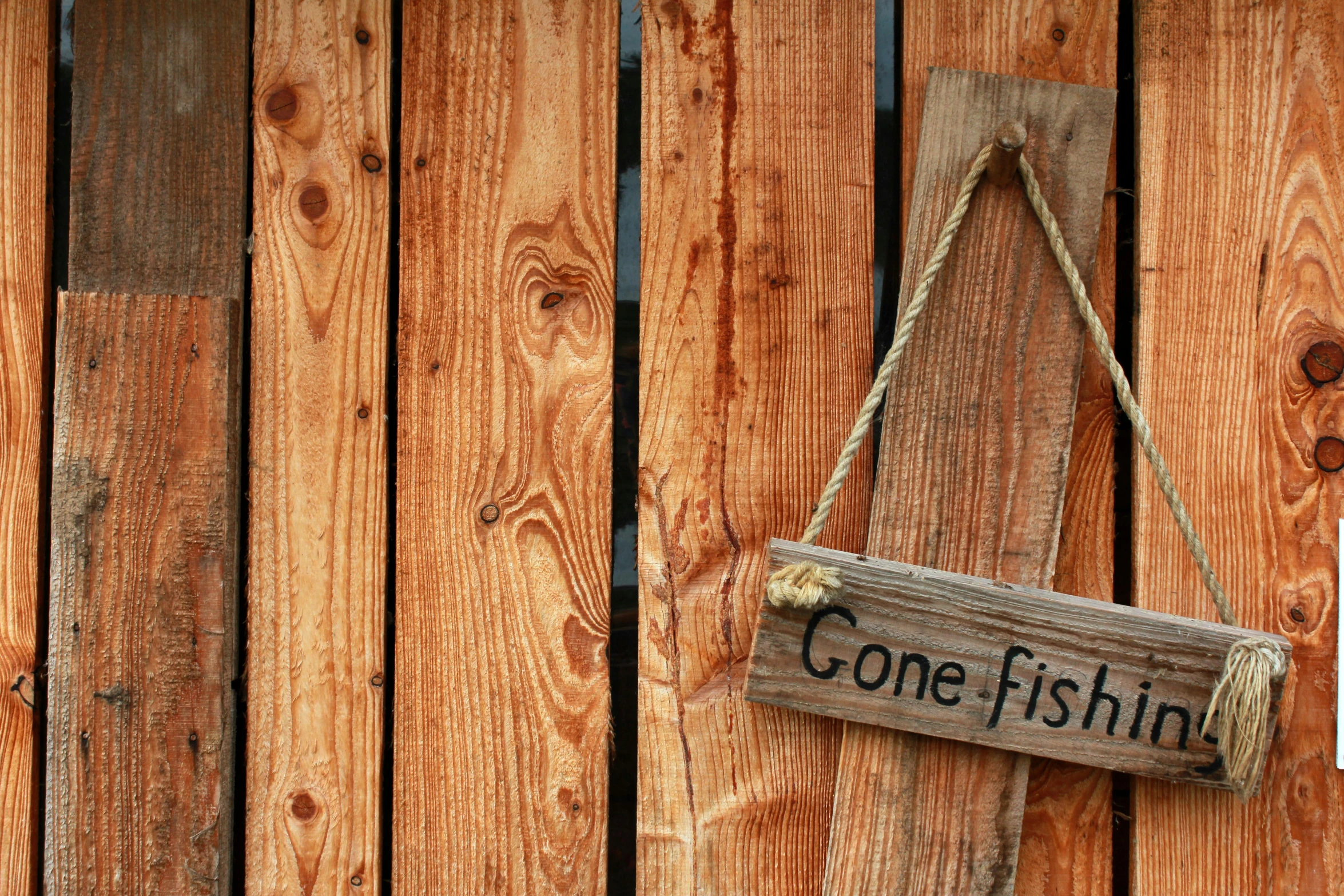 a rustic sign hanging from the side of a wooden fence