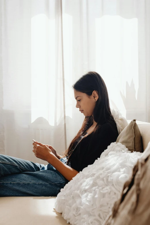 a woman is using her cell phone on the couch