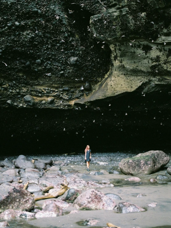 a man standing next to some rocks in the ocean