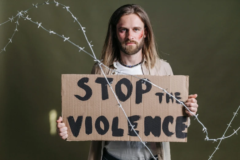 a man holds a sign with barbed wire all around