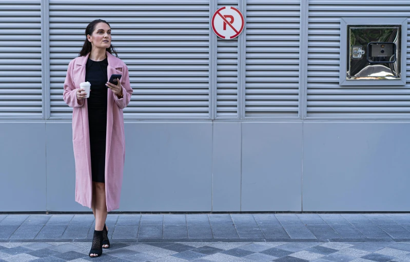 a woman standing by a building with a drink in her hand