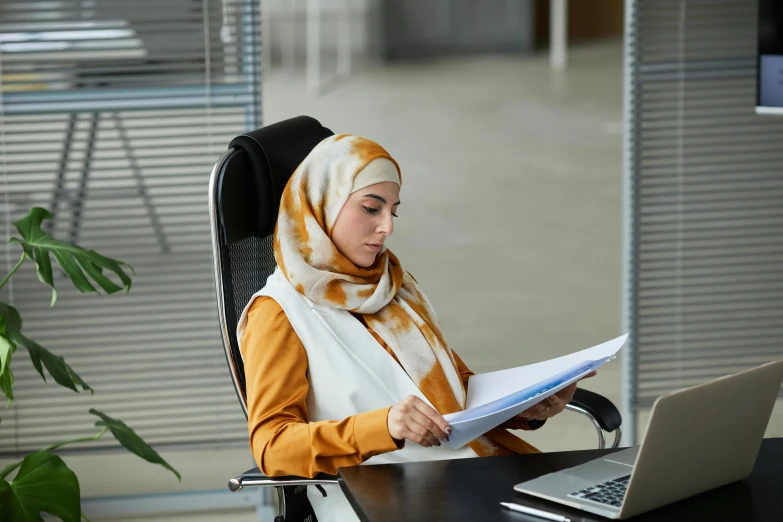 an oriental woman sitting at a desk reading a file