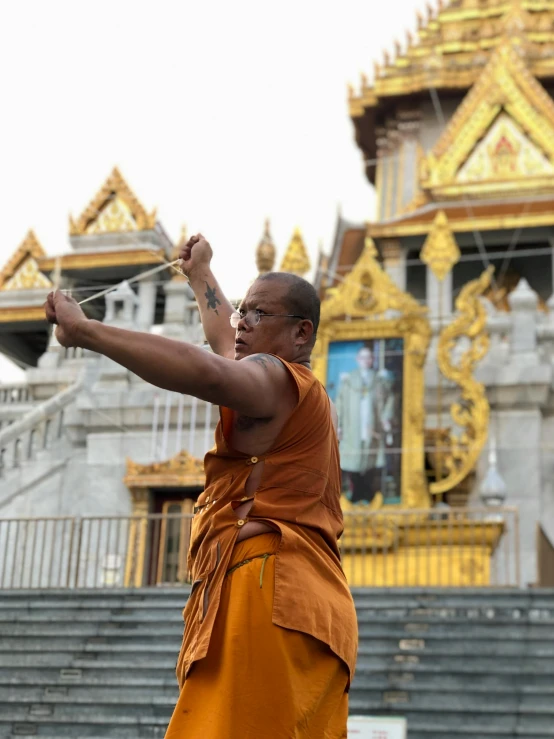 man wearing orange clothes playing in front of an old building