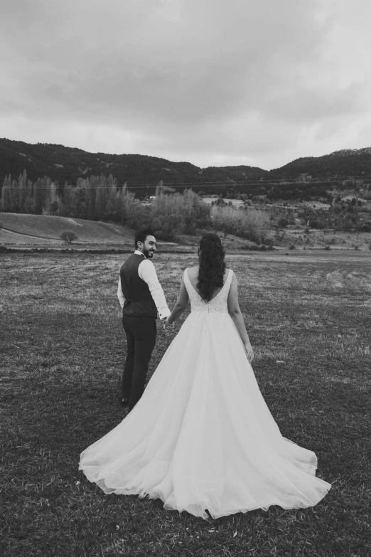 the bride and groom hold hands while walking through the field