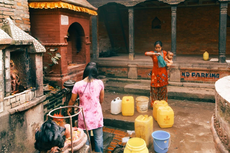 two women pouring water from well into a container