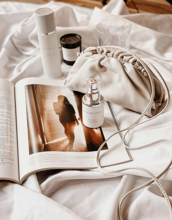 a magazine and cosmetic bottles on a bed